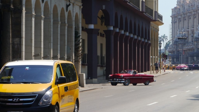Modernes Hyundai Taxi vom Staat und gut erhaltenes Oldtimer Cabriolet im Hintergrund – Havanna, Cuba