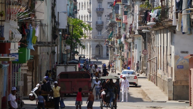 Seitenstraße mit Kubanern, Polizeiauto und Häusern mit Wäsche zum trocknen